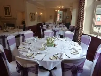 Chairs with purple ribbon round a table.