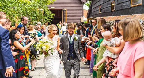 Young white couple just married with confetti thrown at them by wedding guests.