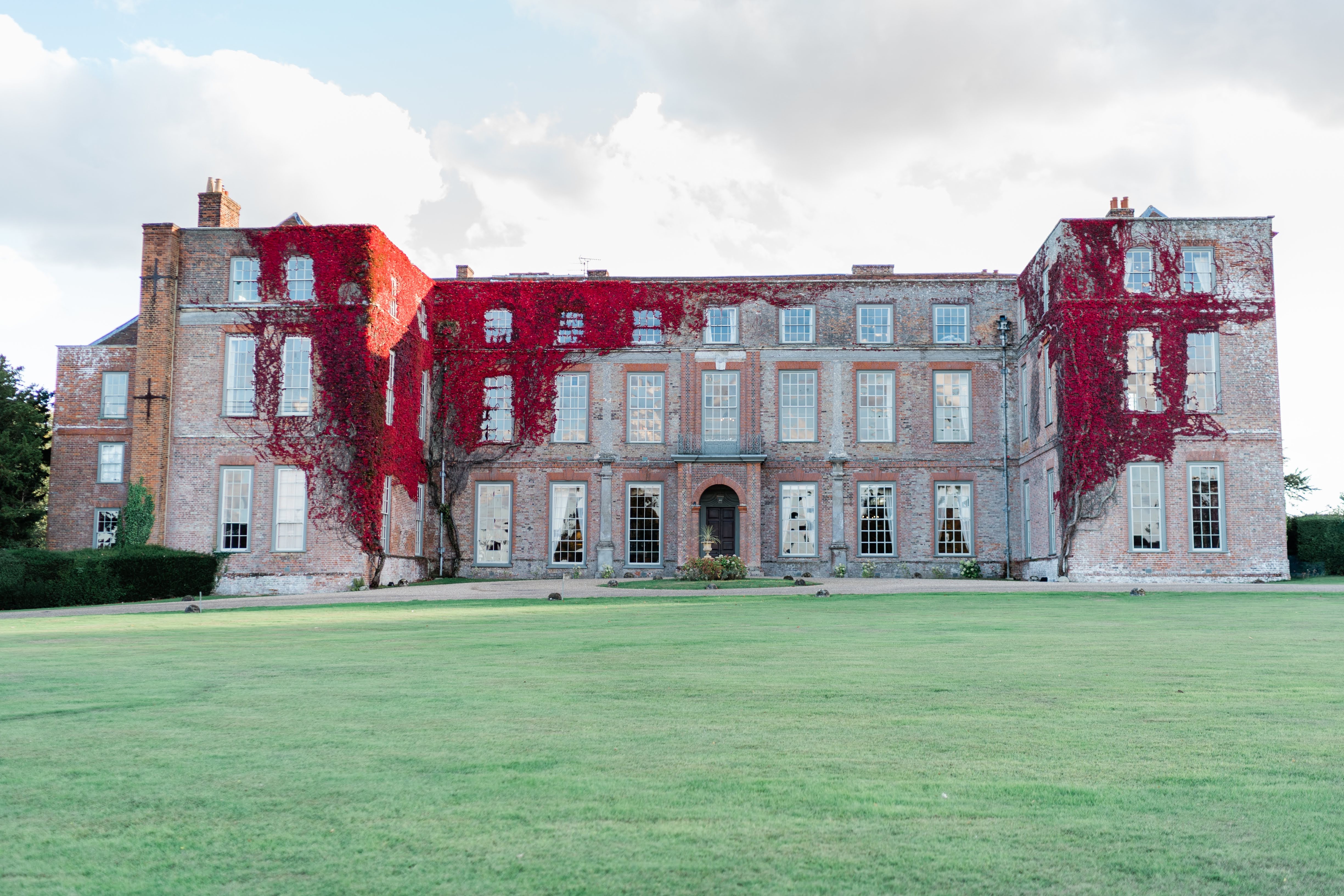 Outside of Glemham Hall with grass in front and red vines growing on the building.