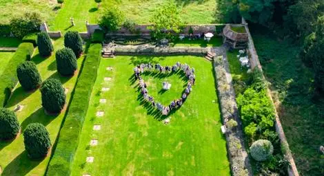 Heart formed by wedding guests on lawn