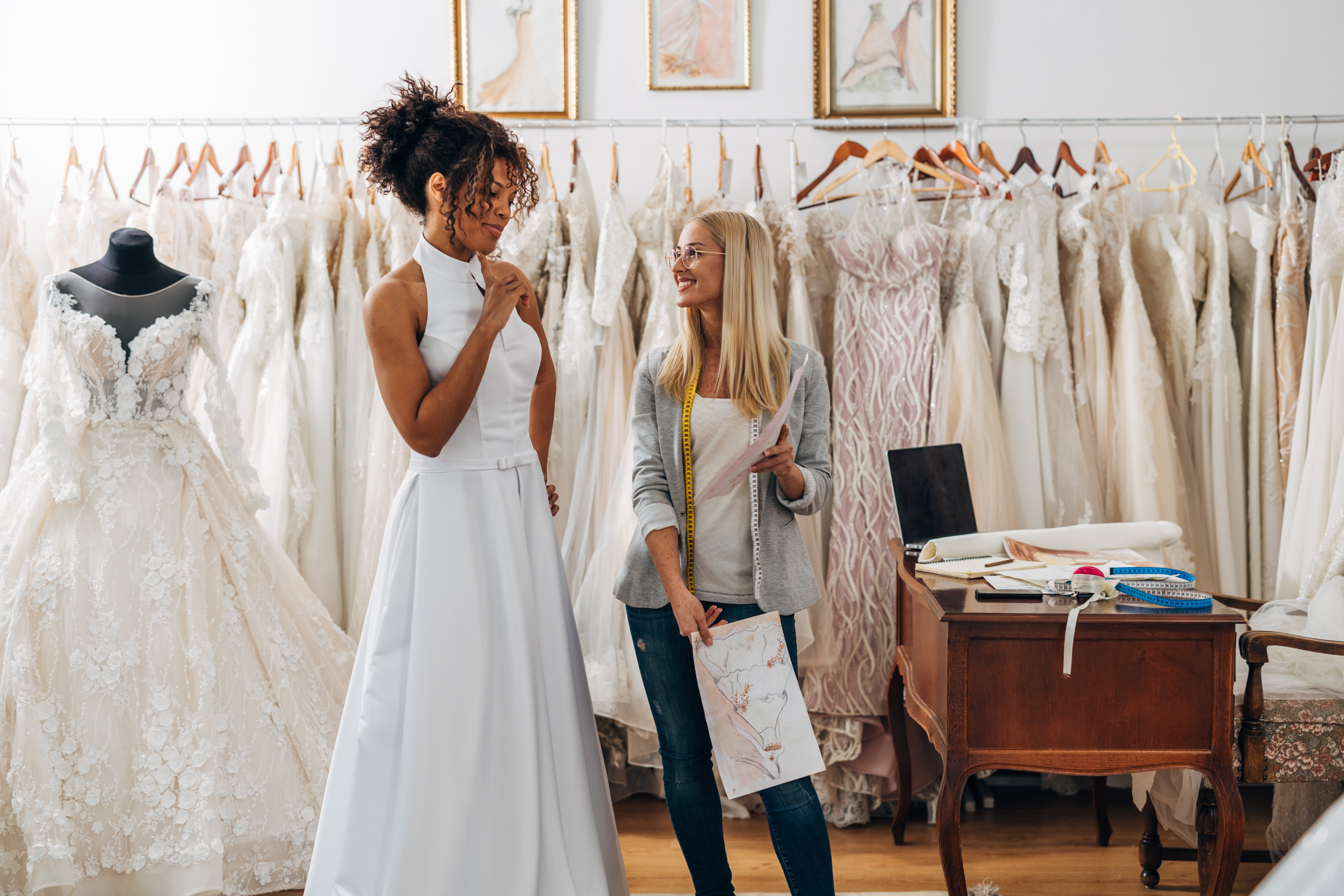 Black bride in her wedding dress chatting with her dress fitter. 