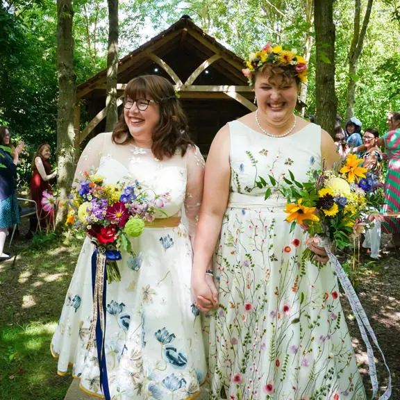 Two women just married holding hands walking back up the aisle. 