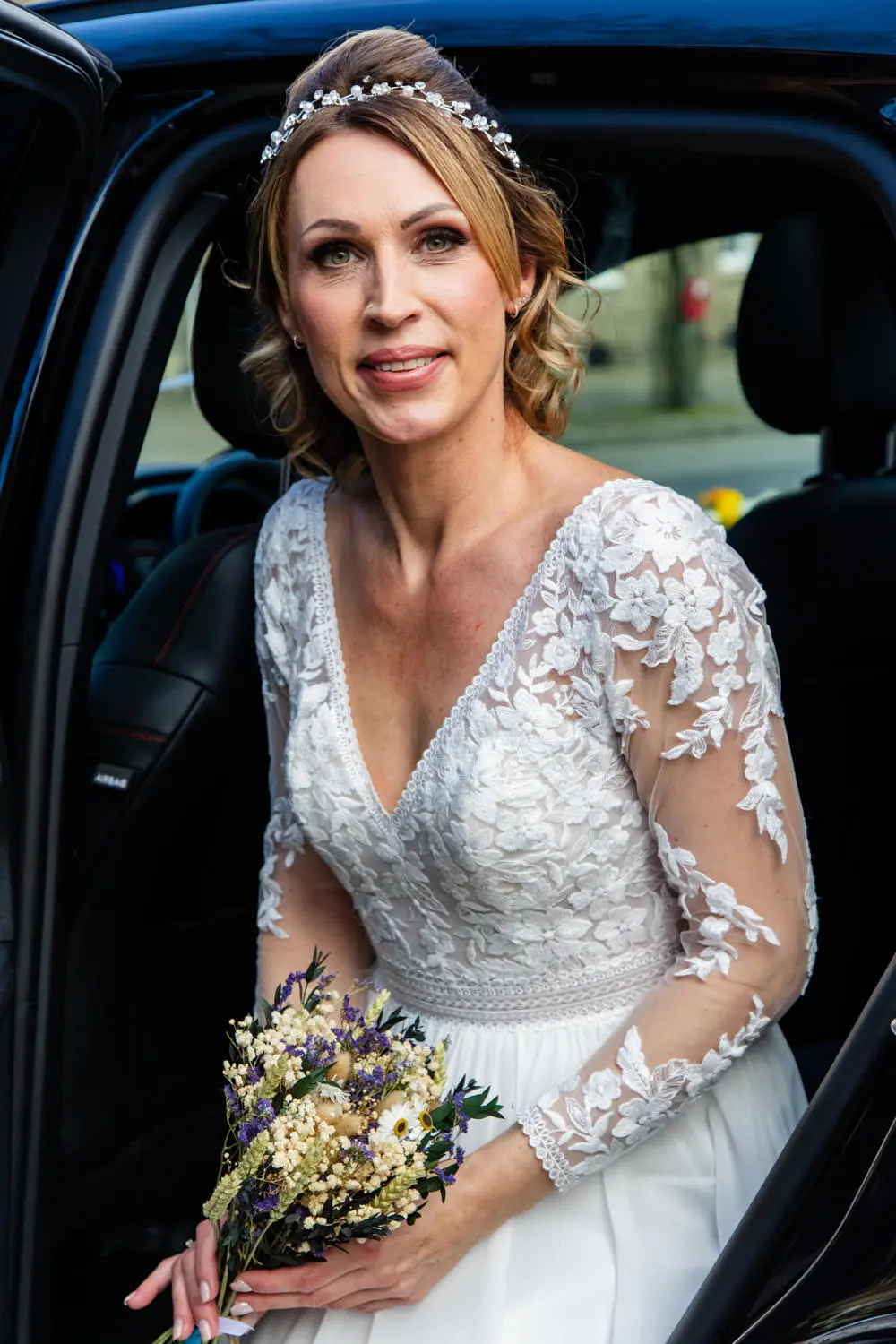Beautiful bride with tiara and lace wedding dress exiting car
