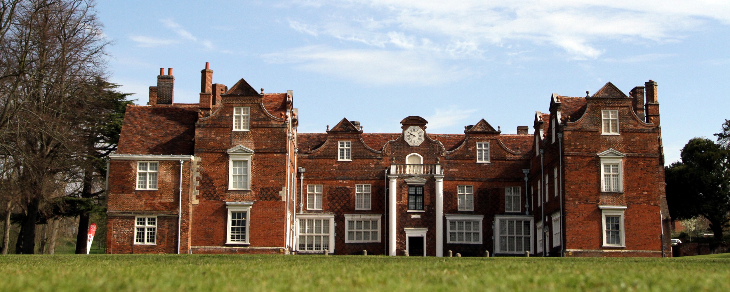 Christchurch Mansion with grass in front and trees behind.