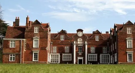 Christchurch Mansion with grass in front and trees behind.