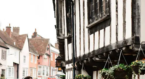 Bride and groom walking in front of Tudor building in Lavenham Suffolk