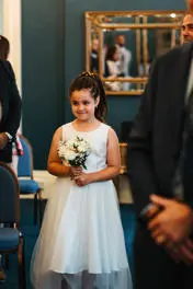Flower girl walking up the aisle with white flowers.