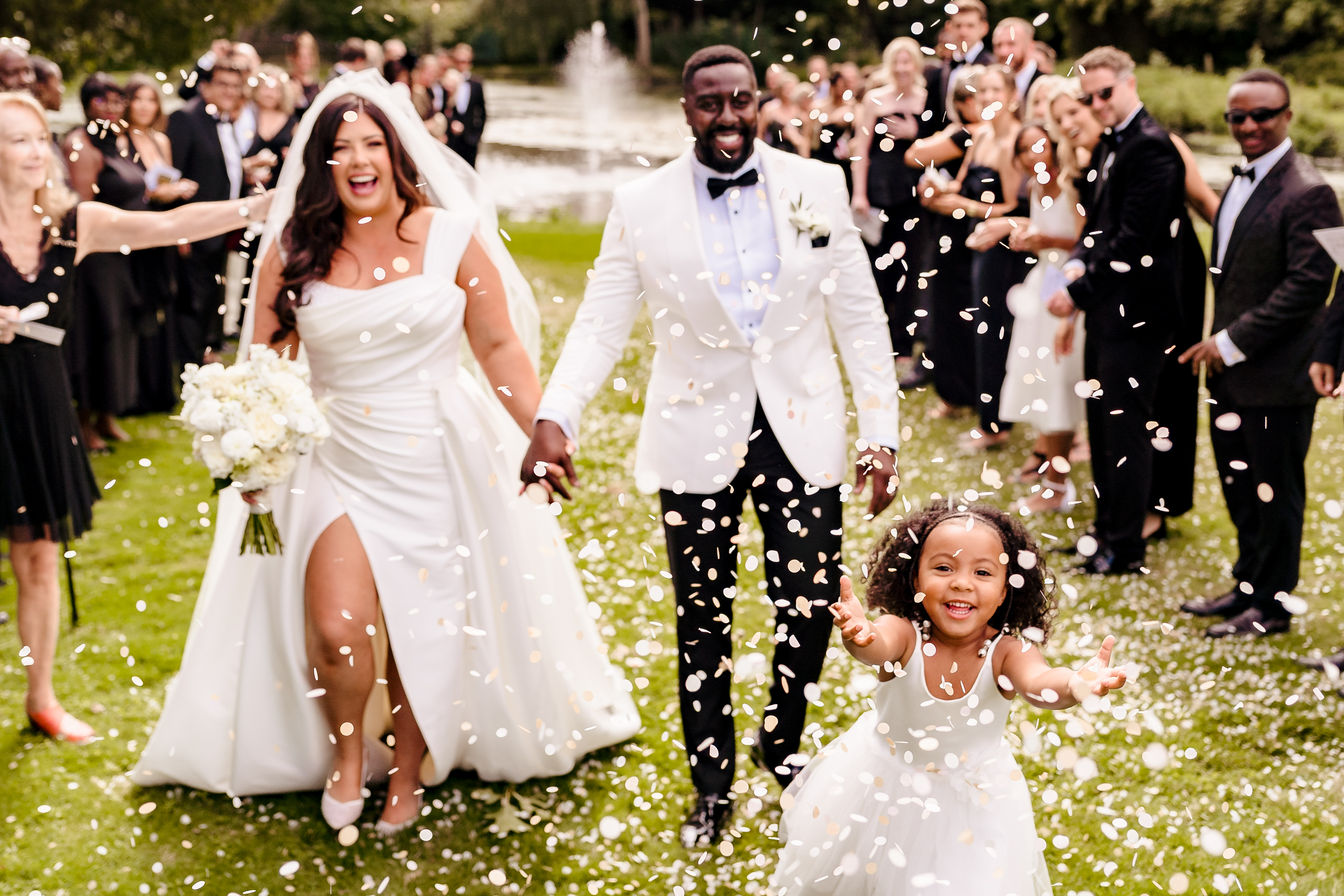 Bride and groom at elegant black tie wedding walking through confetti shower