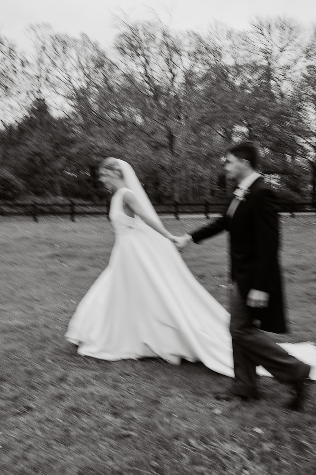 Bride and groom in black and white walking in parkland