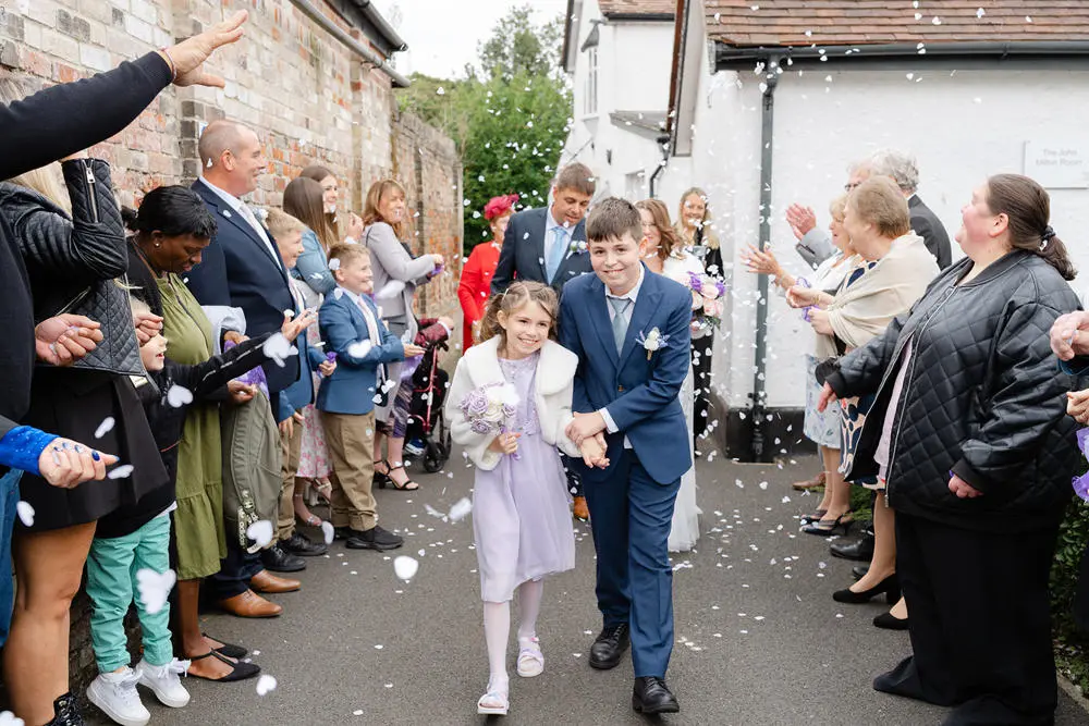 Boy and girl walking out of a wedding ceremony in front of their parents