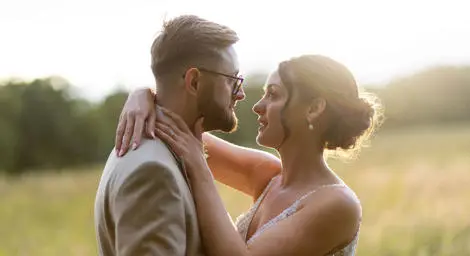 Bride and groom embracing in meadow
