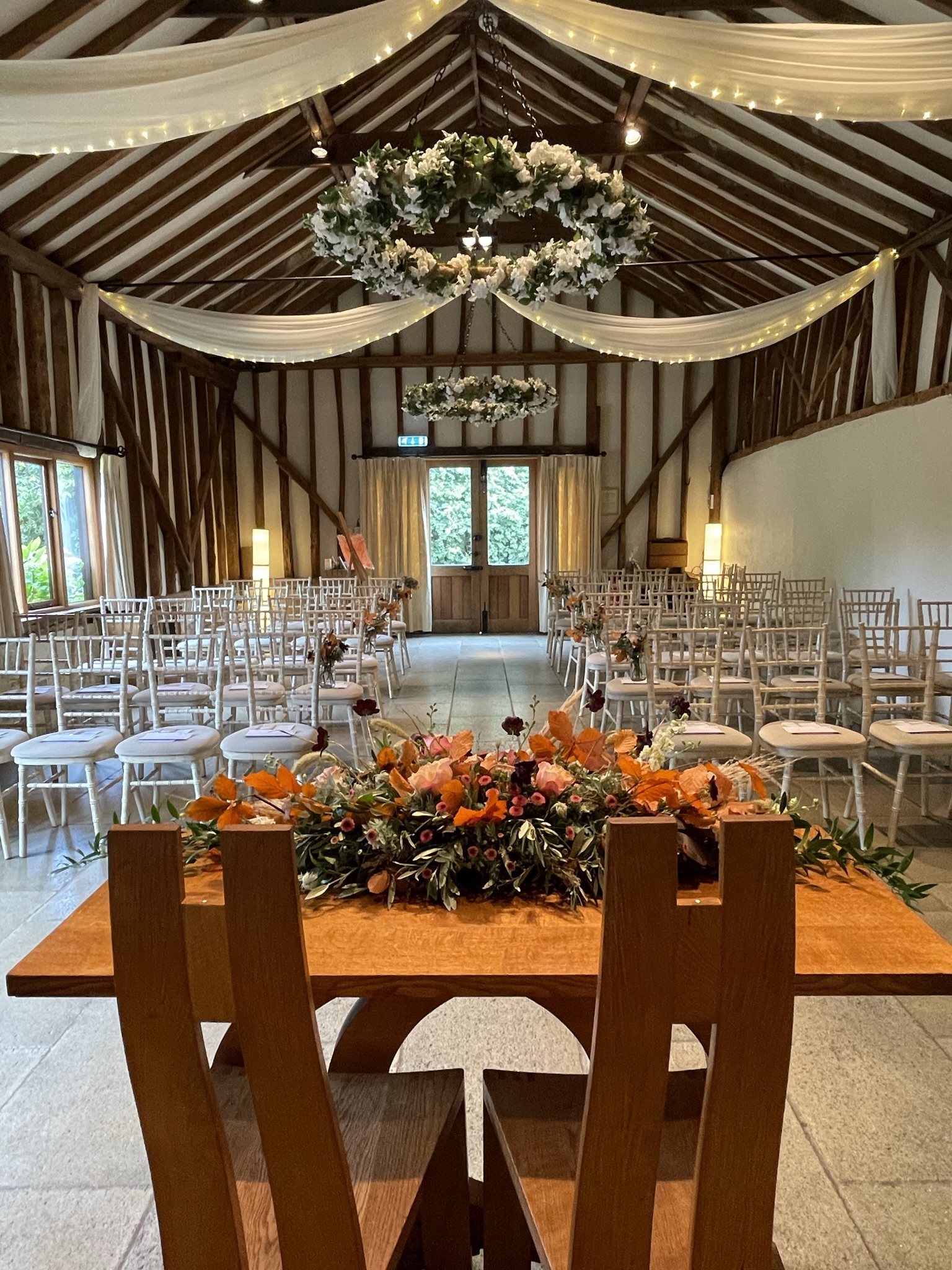 Wedding barn decorated for wedding ceremony white chairs, flowers on table