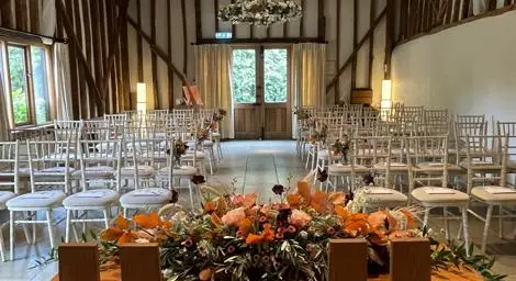 Wedding barn decorated for wedding ceremony white chairs, flowers on table