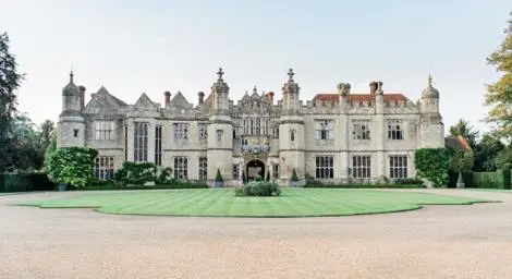 Outside of Hengrave Hall with driveway and grass in front.