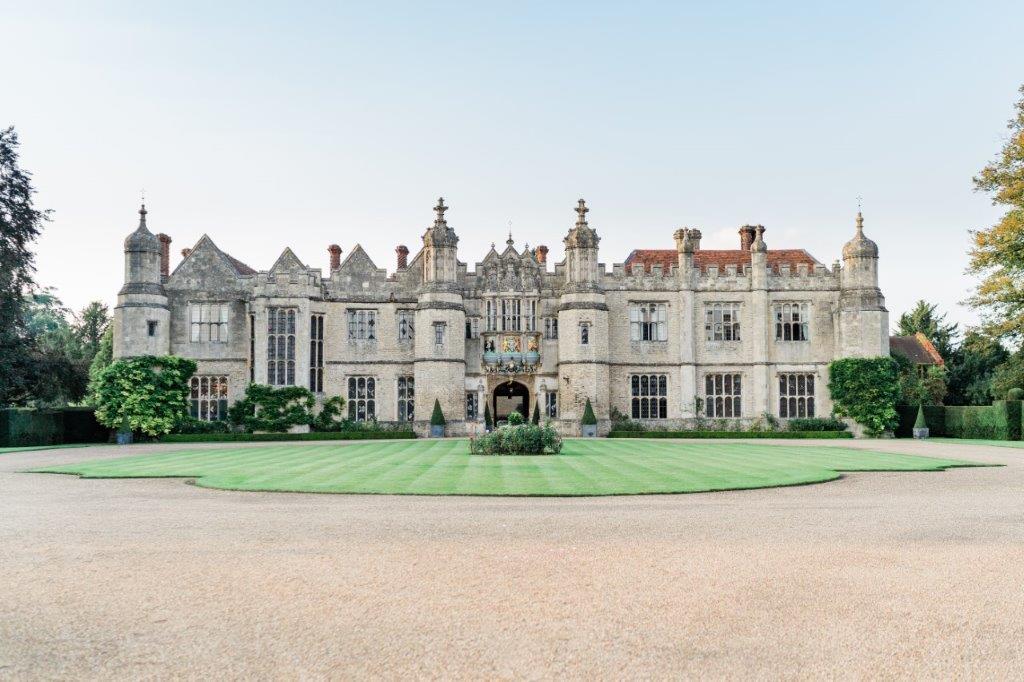 Outside of Hengrave Hall with driveway and grass in front. 