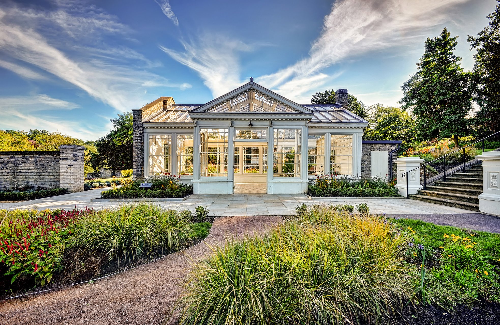 Outside Holywells Orangery with patio outside and path with shrubs either side of it leading up to the building.