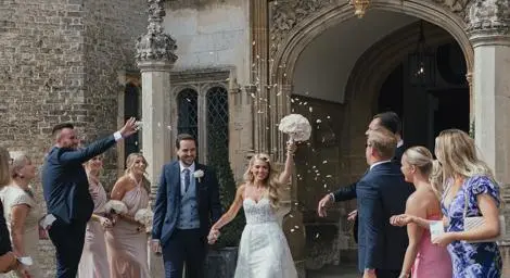 Bride and groom just married coming out of their venue holding hands.