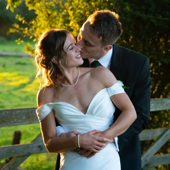 Groom hugging bride and kissing her on the cheek.
