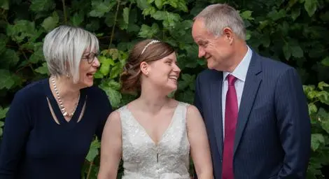 Bride flanked by her parents, all smiling at each other happily