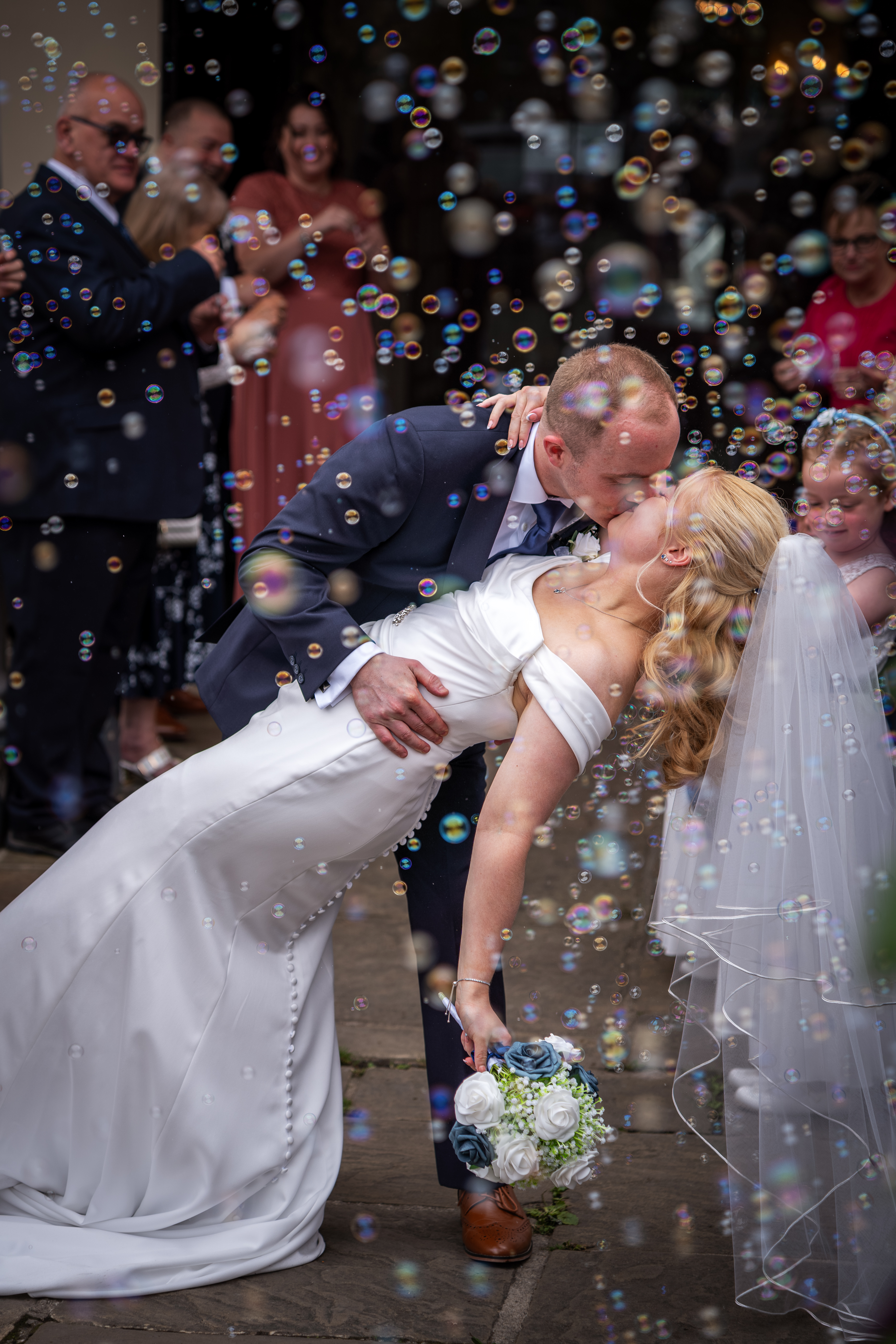 Groom kissing bride amidst bubbles