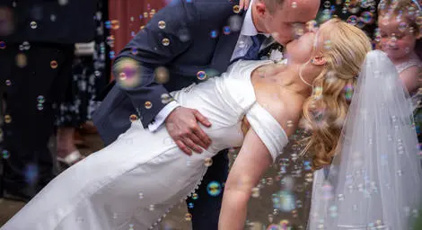 Groom kissing bride amidst bubbles