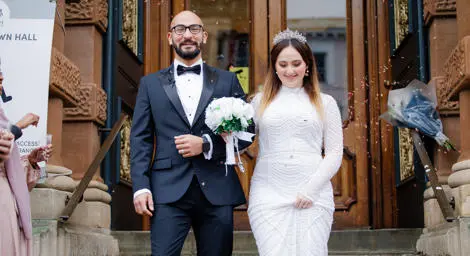 Bride and groom arm in arm after getting married with confetti thrown at them