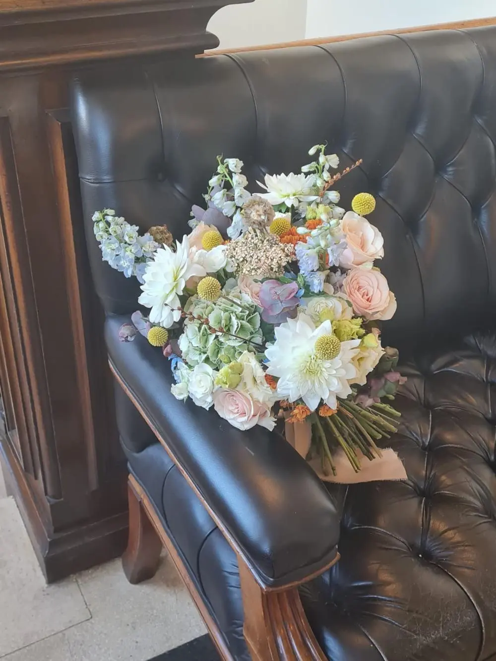 Beautiful bridal bouquet in spring pastel colours on black leather sofa