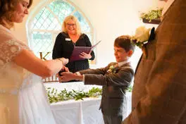 Page boy handing over rings to the bride. 