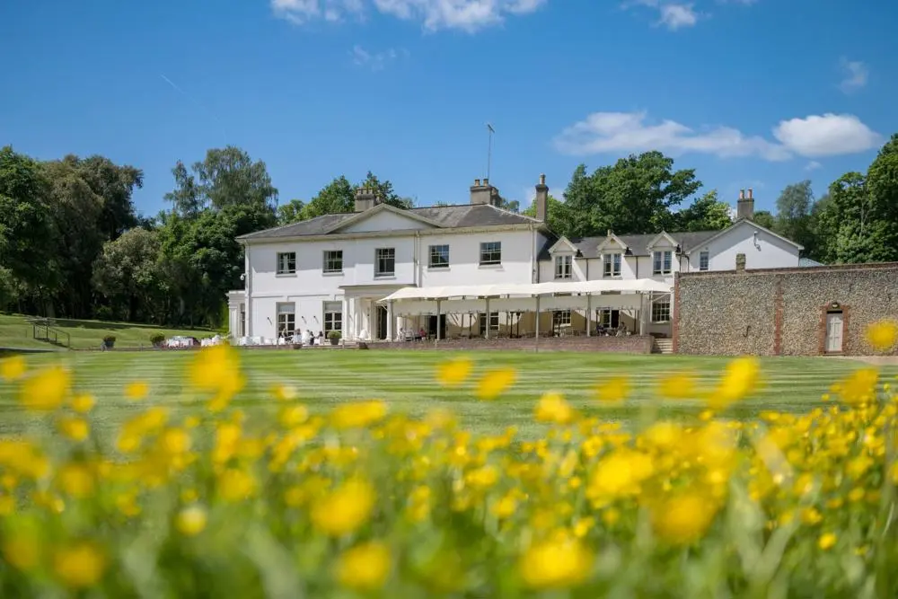 Outside Kesgrave Hall with grass and yellow flowers in front.