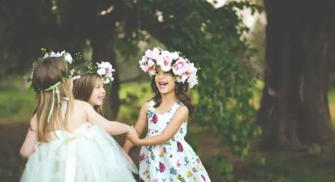 Three little girls dancing with flower crowns