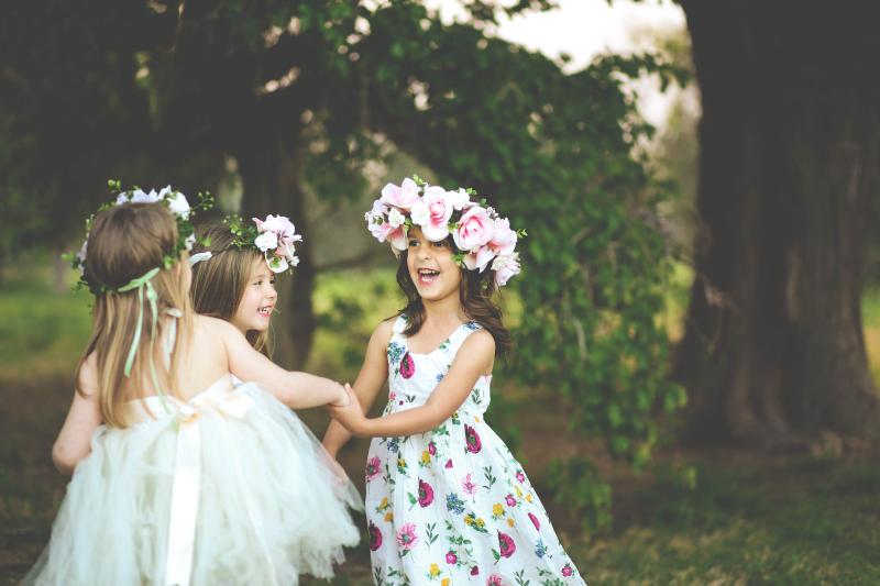 Three little girls dancing with flower crowns