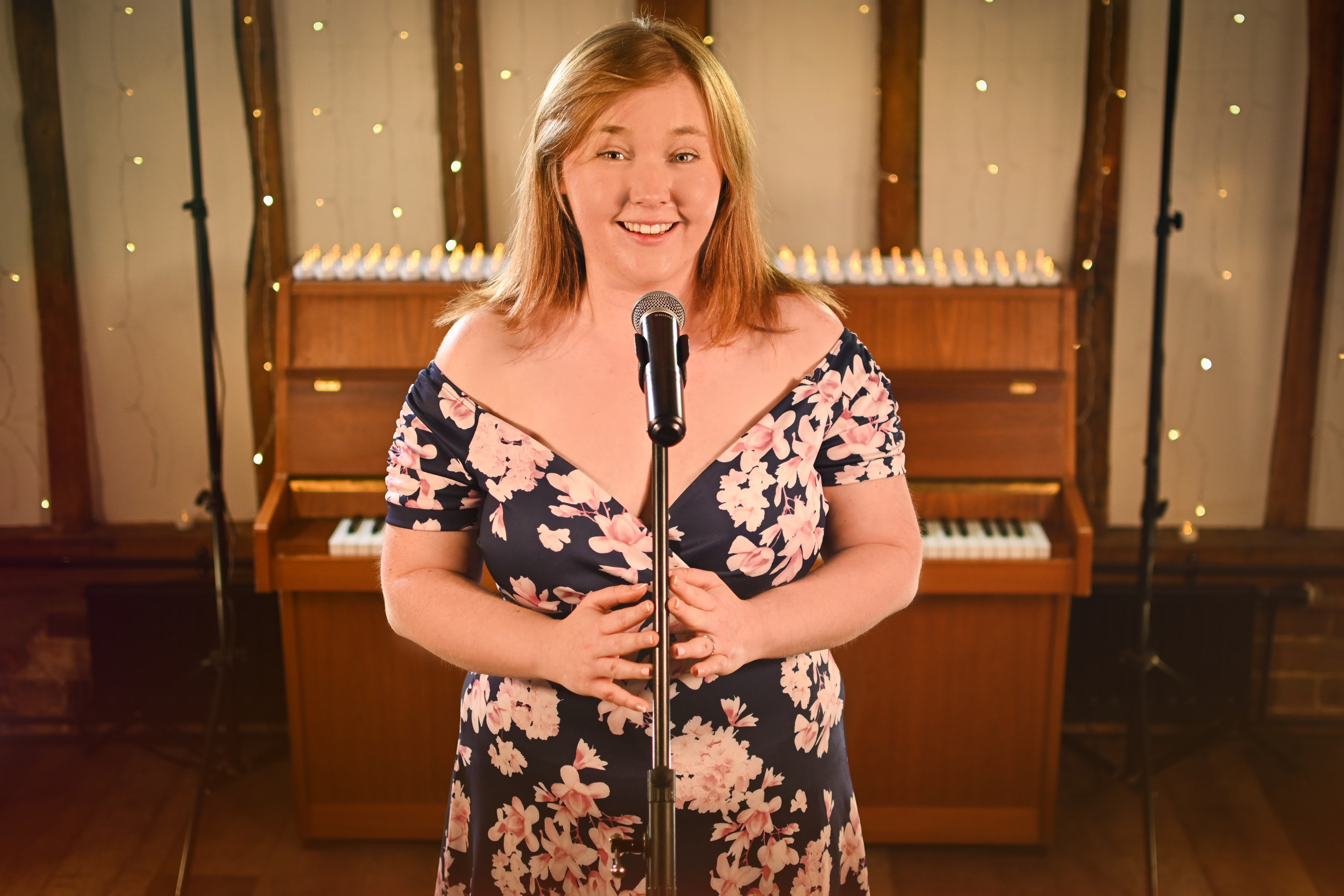 Naomi Collins Vocalist standing behind mic with a piano in the background