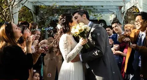 Bride and groom kissing amongst their friends