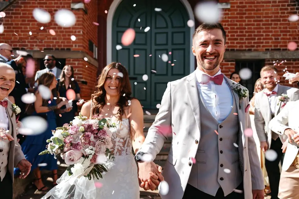 Bride and groom smiling happily in a confetti shower