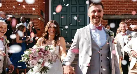 Bride and groom smiling happily in a confetti shower