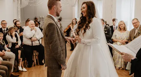 Bride and groom at ring exchange smiling happily at each other