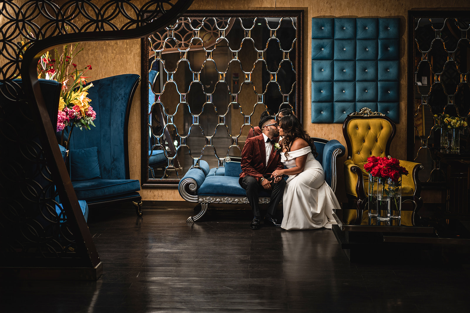 Bride and groom kissing on sofa in opulent room