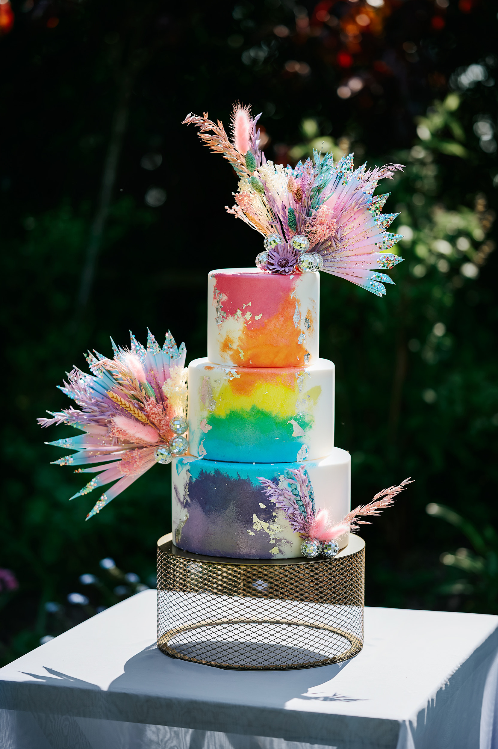 Three tier rainbow coloured cake with decorations