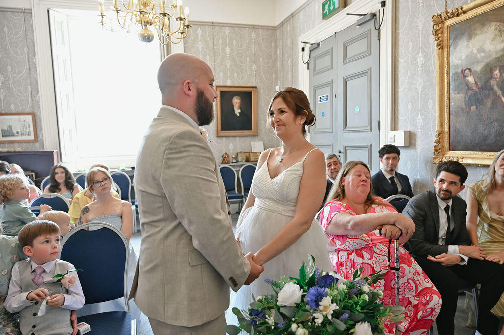 Bride and groom holding hands during their ceremony at Sudbury Town Hall