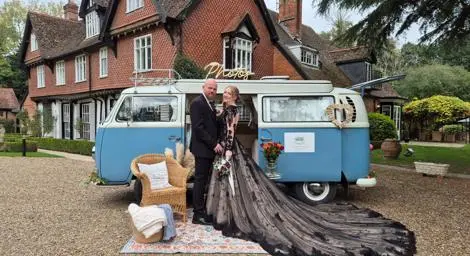 Blue and white campervan photo booth parked in front of stately building with couple