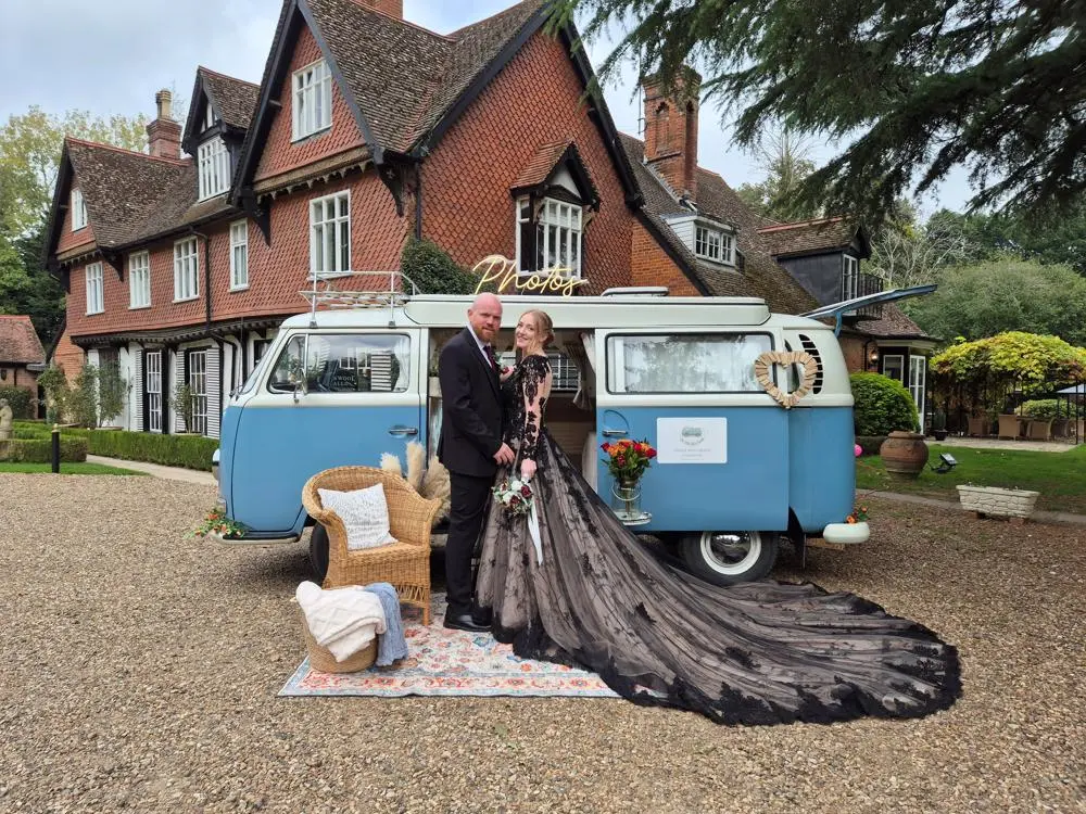 Blue and white campervan photo booth parked in front of stately building with couple