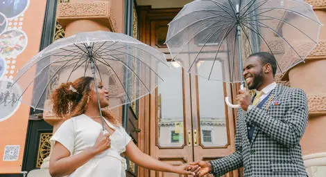 Chic bride and groom with umbrellas in front of Ipswich Town Hall