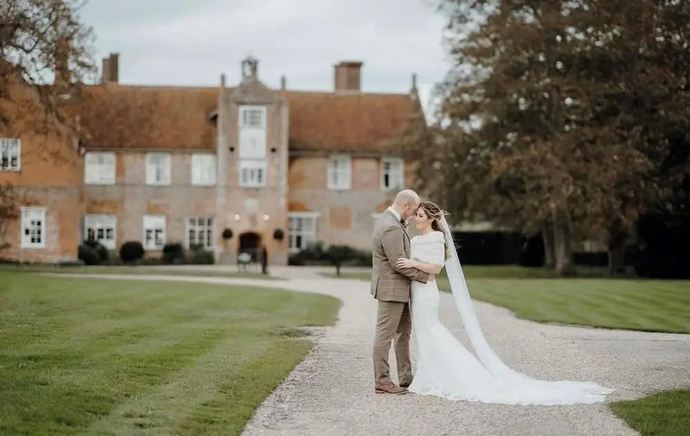 Bride and groom embracing in front of country house
