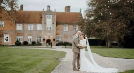 Bride and groom embracing in front of country house