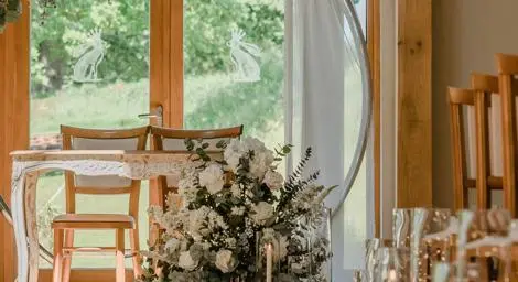 Flower arch with white flowers above table and chairs