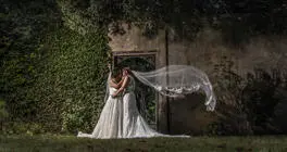 Two brides kissing with one veil blown in the wind