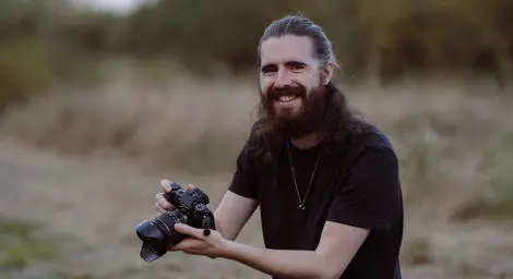 Tom Juggins Suffolk Wedding Photographer kneeling holding a camera