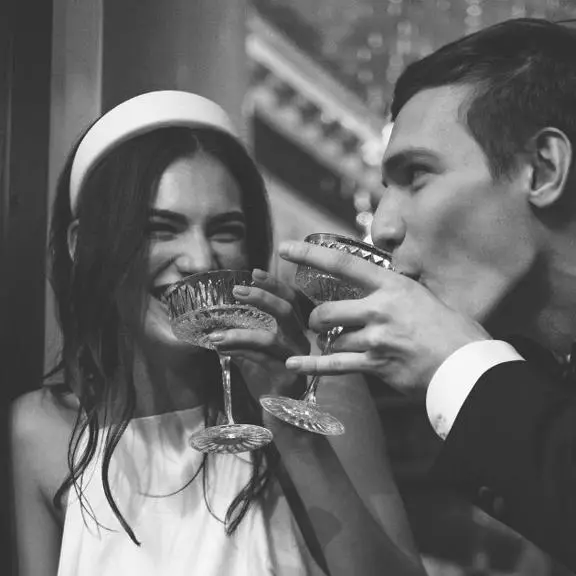 Young bride and groom drinking champagne toasting each other.