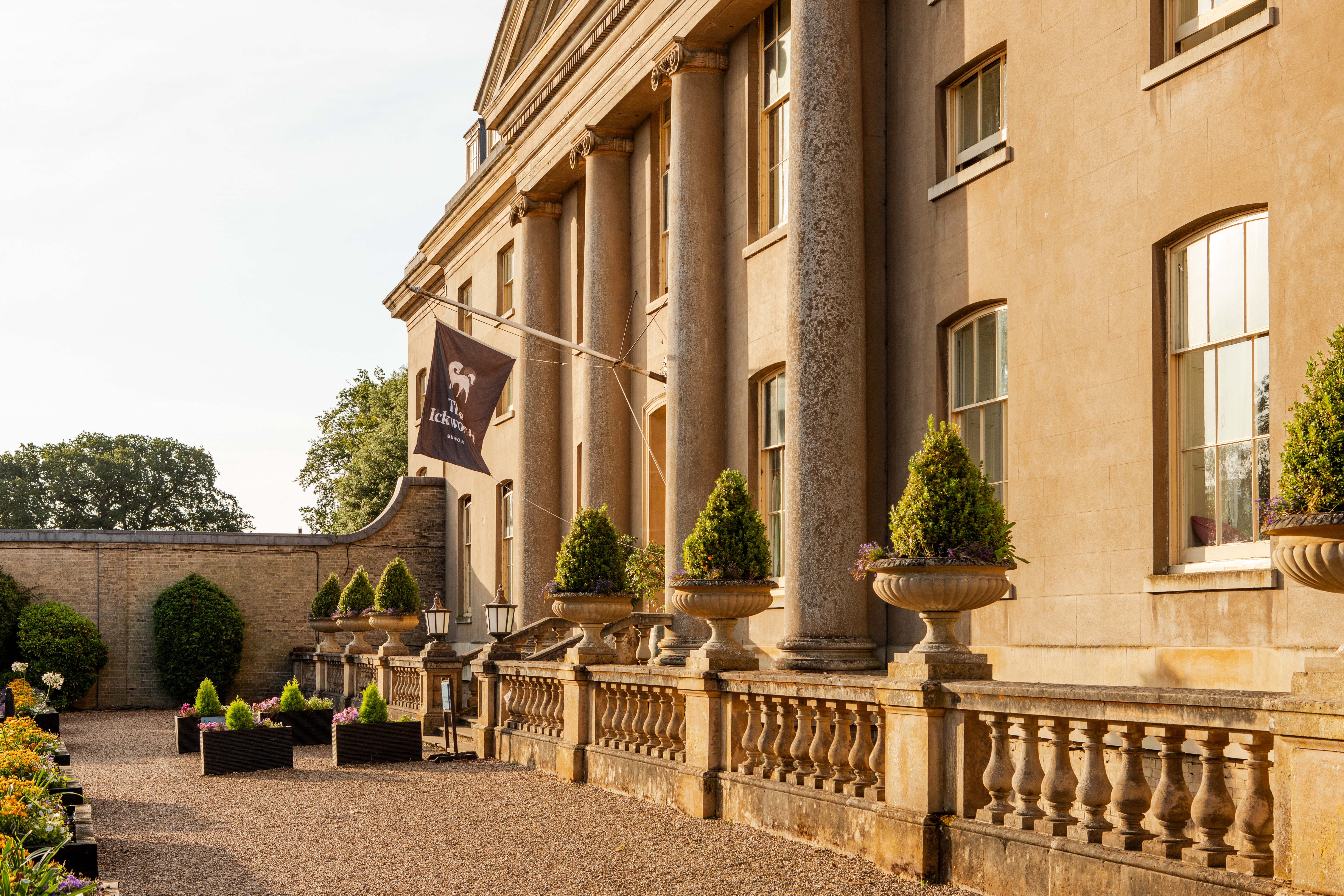 Ickworth House Hotel grand country house entrance with sand coloured facade and trees in planters