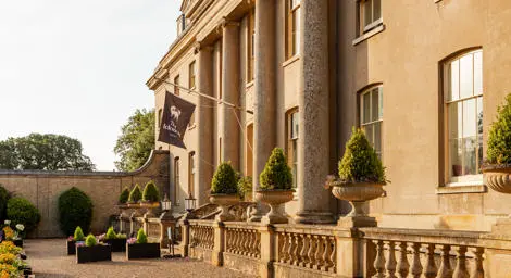 Ickworth House Hotel grand country house entrance with sand coloured facade and trees in planters